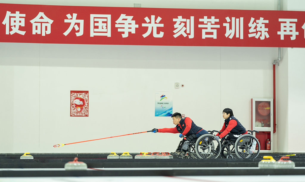 12月23日，在北京順義中國殘疾人體育運動管理中心的國家殘疾人冰上運動比賽訓(xùn)練館，中國輪椅冰壺隊隊員張明亮（左）、張曈在訓(xùn)練。新華社記者 才揚 攝