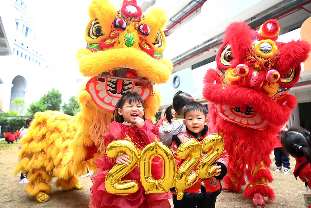 12月31日，在廣西柳州市一家幼兒園，兩名孩子在舞獅隊前展示“2022”字樣。新華社發(fā)（黎寒池攝）