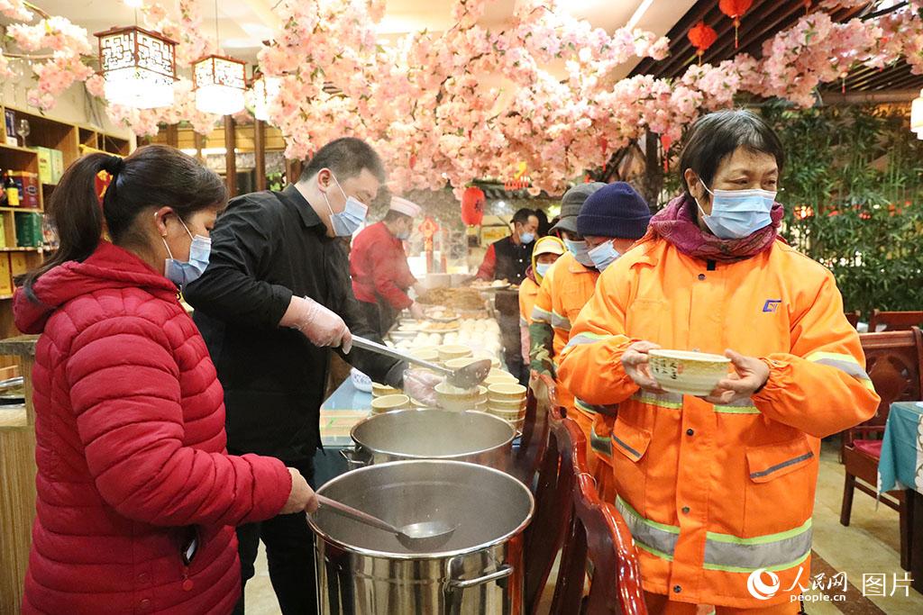 1月10日，店里的服務(wù)人員在給環(huán)衛(wèi)工人盛上熱騰騰的臘八粥。張進剛攝