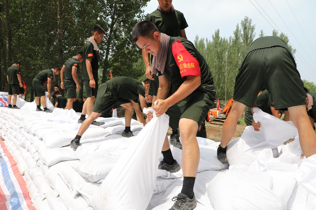 武警天津總隊(duì)某支隊(duì)官兵在子牙河天津靜海段搬運(yùn)沙袋加固堤壩（8月8日攝）。新華社記者 李秉宣 攝