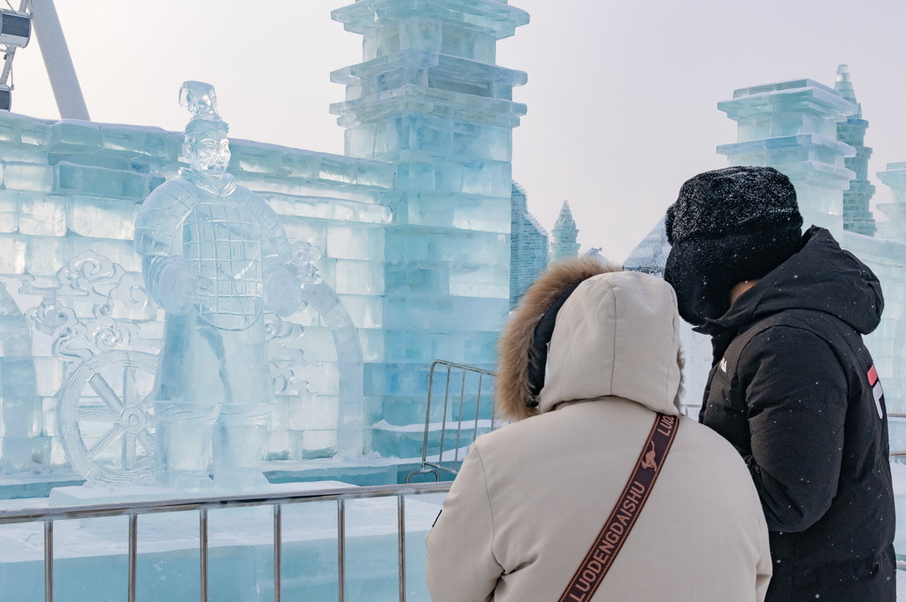 1月23日，在哈爾濱冰雪大世界園區(qū)，游客在“冰馬俑”冰雕前游玩。