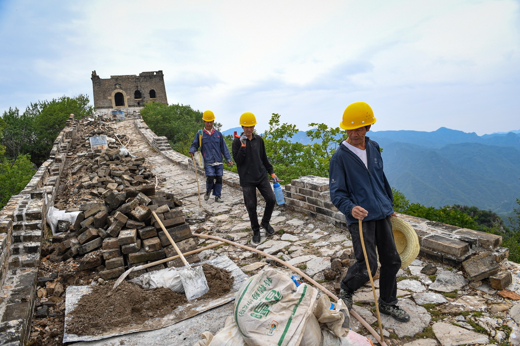 工人們走在箭扣長城122號敵臺東側墻體修繕施工現場（7月2日攝）。