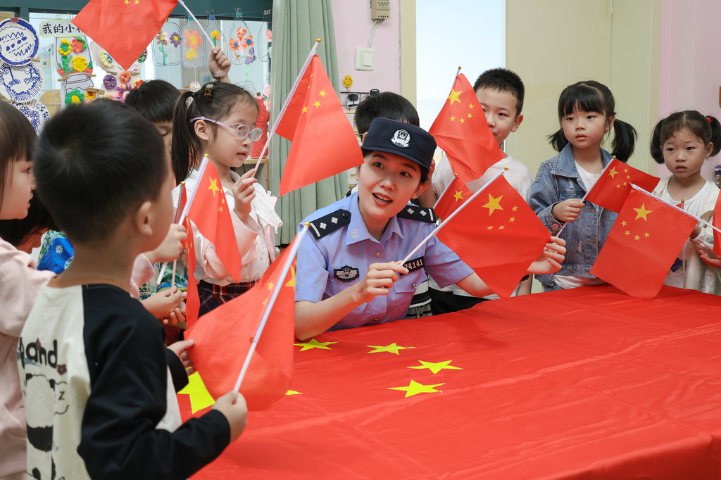 9月25日，浙江省臺州市三門縣公安局珠岙派出所民警在鎮(zhèn)中心幼兒園給小朋友講國旗知識。新華社發(fā)（林利軍攝）