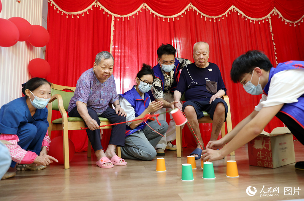 10月9日，在海南省?？谑叙B(yǎng)老服務(wù)中心，大學(xué)生志愿者和老人一同參與互動(dòng)小游戲。人民網(wǎng)記者 符武平攝