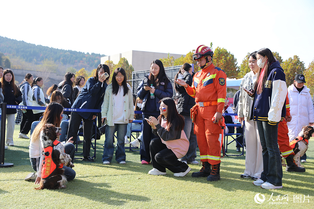 11月8日，“119”消防宣傳月山東消防隊(duì)站開(kāi)放日現(xiàn)場(chǎng)，大學(xué)生們爭(zhēng)相與搜救犬合影。人民網(wǎng)記者 劉祺攝