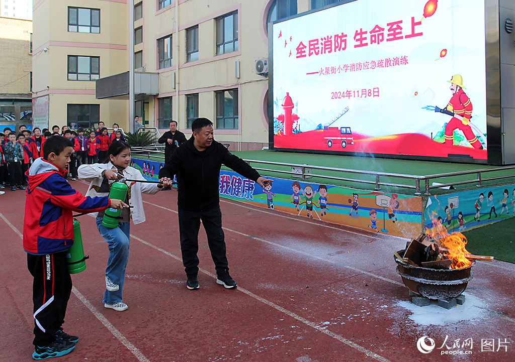 11月8日，甘肅省蘭州市火星街小學(xué)開(kāi)展“全民消防 生命至上”消防應(yīng)急疏散演練活動(dòng)。老師指導(dǎo)學(xué)生如何正確使用滅火器。人民網(wǎng)記者 米媛攝