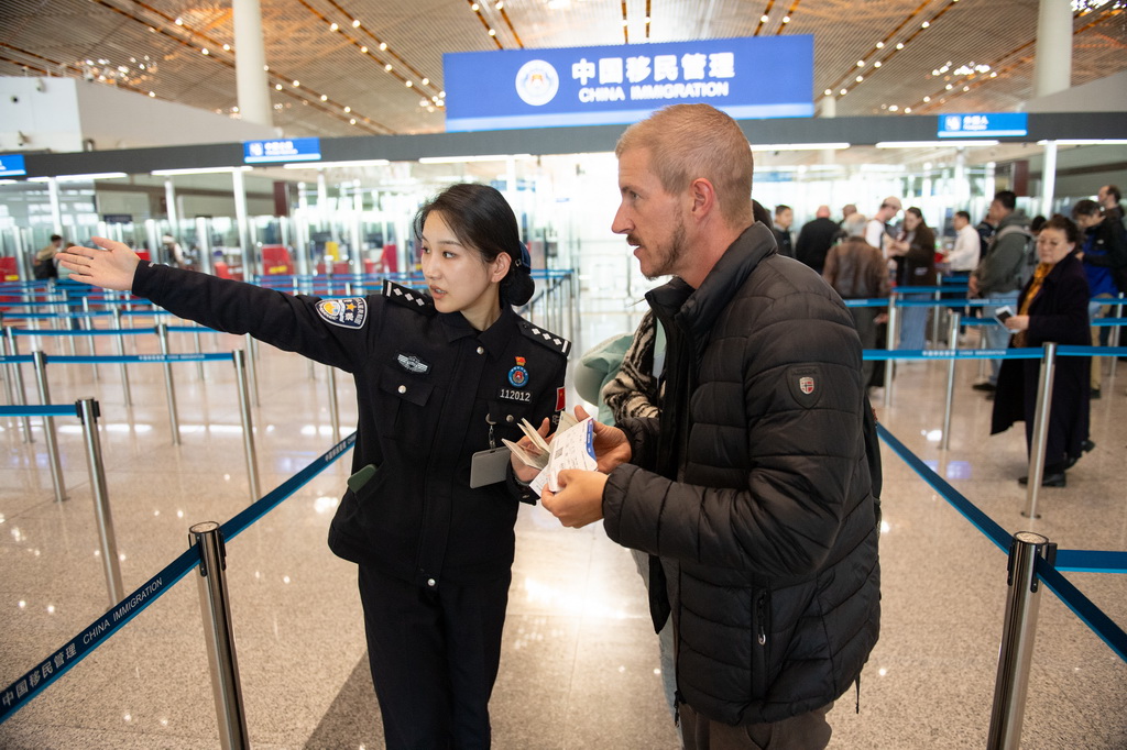 12月4日，邊檢民警在北京首都機(jī)場三號航站樓邊檢入境現(xiàn)場引導(dǎo)外國游客。新華社記者 陳鐘昊 攝