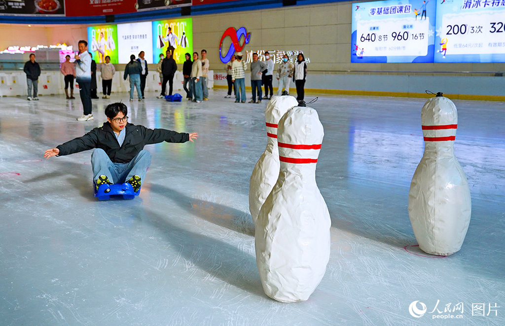 11月29日，江西省贛州市章貢區(qū)的一家室內(nèi)真冰滑冰場，冰雪運動愛好者在參與體驗趣味冰上運動會“冰上保齡球”項目。人民網(wǎng) 朱海鵬攝