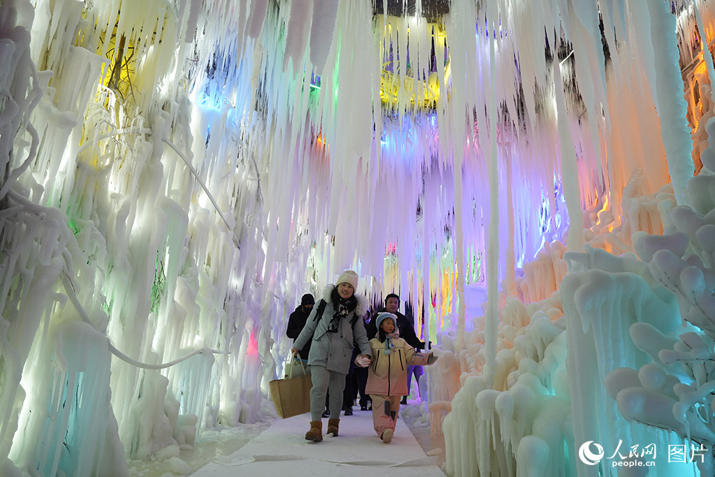 12月16日，游客在吉林長春冰雪新天地景區(qū)的冰洞里欣賞冰雕藝術(shù)。人民網(wǎng)記者 李洋攝