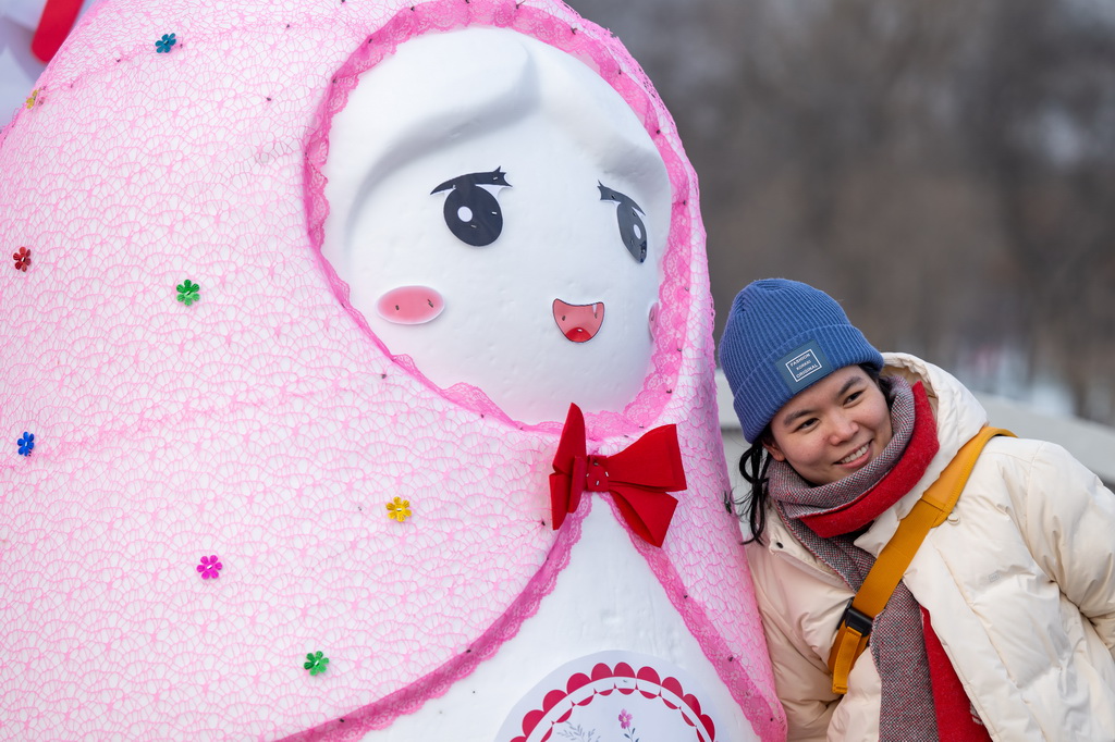 12月23日，一名游客在第37屆太陽島國(guó)際雪雕藝術(shù)博覽會(huì)上拍照留念。新華社記者 張濤 攝