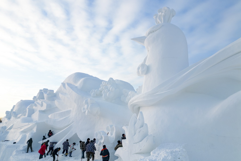 12月23日，雕刻師在哈爾濱太陽島雪博會園區(qū)創(chuàng)作大型雪雕（無人機(jī)照片）。新華社記者 張濤 攝