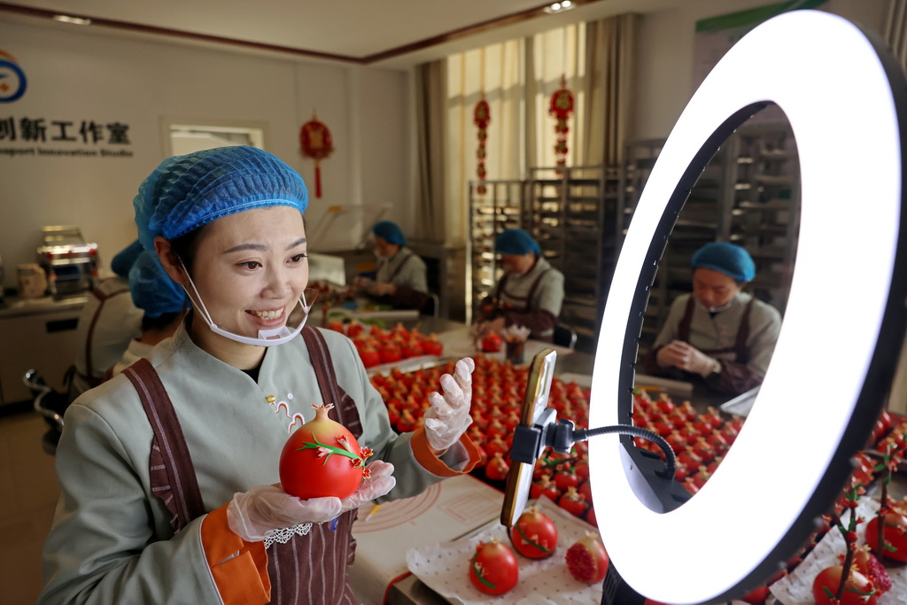 12月29日，在山東省棗莊市“紅石榴”喜饃制作工坊，民間藝人通過網(wǎng)絡(luò)直播介紹“紅石榴”喜饃制作方法。新華社發(fā)（孫中喆攝）