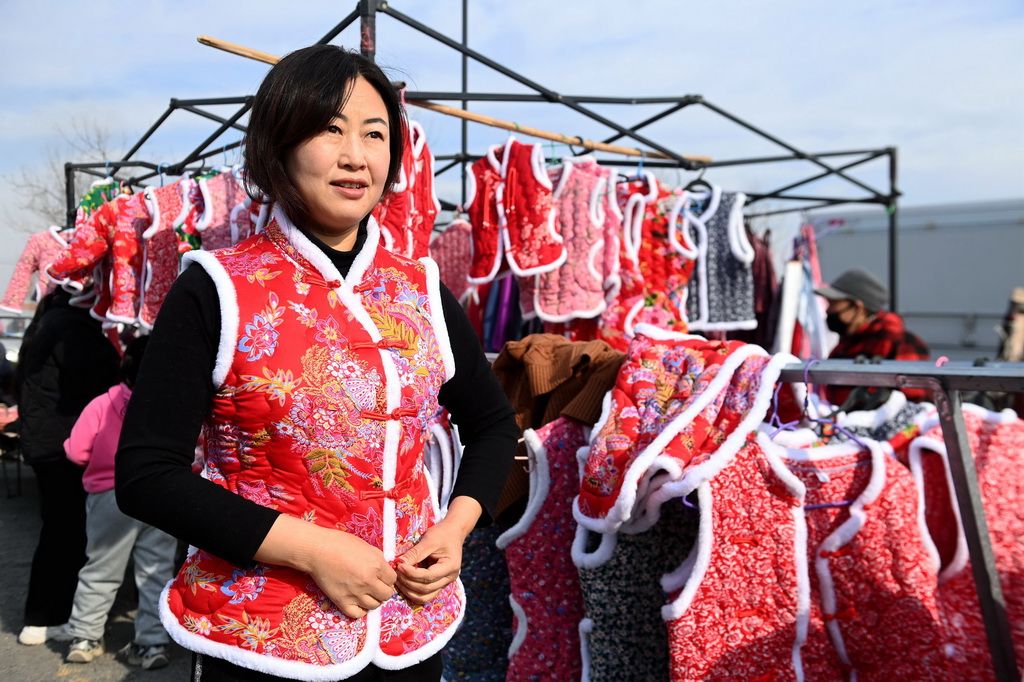 12月29日，在山東青島西海岸新區(qū)泊里大集，一名消費者在試穿新年喜慶服裝。新華社發(fā)（俞方平攝）