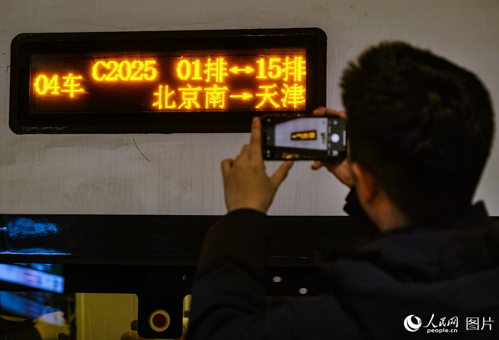 12月30日，旅客在站臺用手機(jī)拍攝C2025次列車車次留作紀(jì)念。