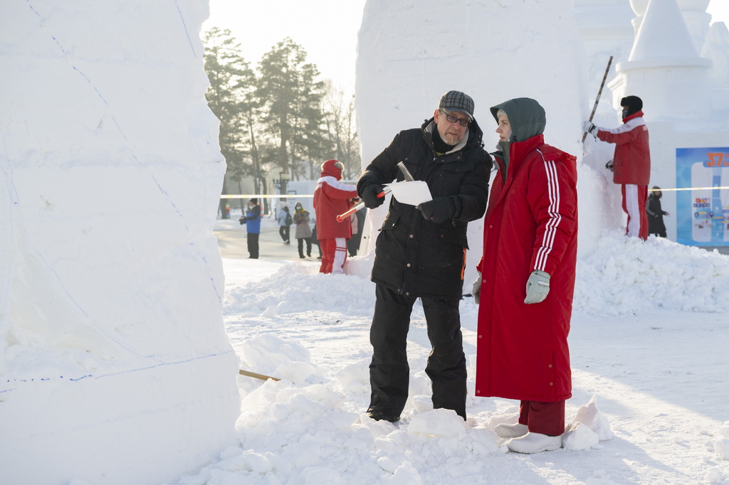 1月6日，在哈爾濱太陽島雪博會園區(qū)，參賽選手在雕刻雪雕作品的間隙交流。新華社記者 謝劍飛 攝