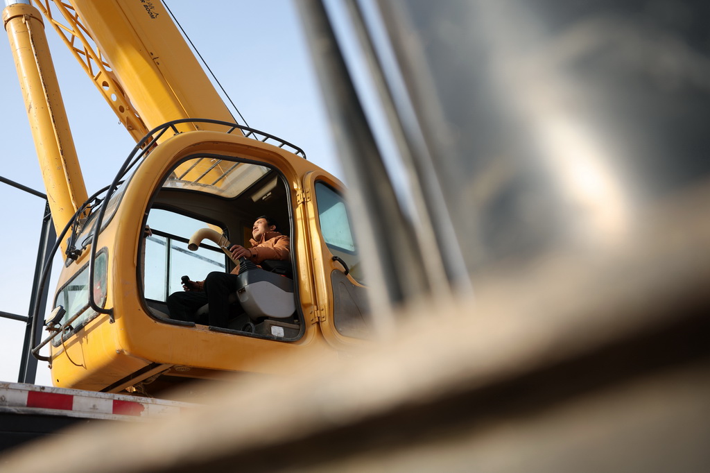 一位吊車司機在中鐵二十局承建的甘肅臨夏綜合物流園項目建設(shè)現(xiàn)場進行起吊作業(yè)（1月6日攝）。