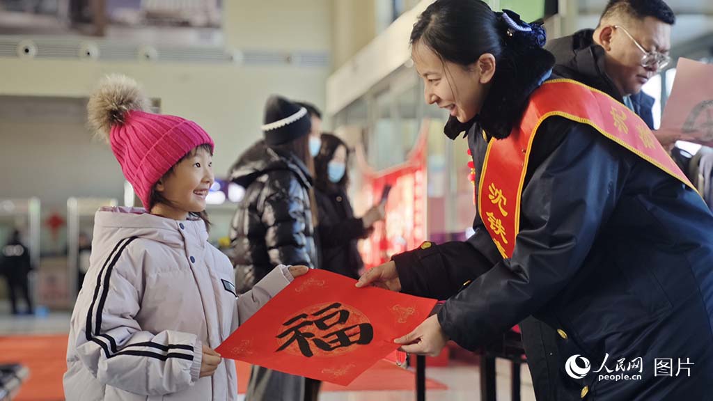 2025年春運(yùn)首日，國鐵沈陽局長春車務(wù)段公主嶺南站候車室內(nèi)文化活動異彩紛呈，鐵路工作人員為旅客送春聯(lián)、“福”字，春運(yùn)在濃濃的年味中拉開序幕。人民網(wǎng)記者 王海躍攝