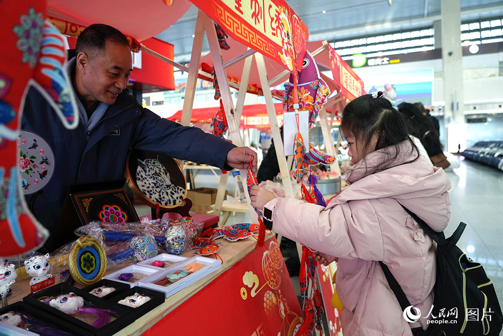 2025年春運(yùn)首日，“多彩民俗迎春運(yùn)”活動在西寧火車站候車大廳內(nèi)舉辦，刺繡展柜上各種各樣的非遺和文創(chuàng)產(chǎn)品引得旅客駐足圍觀。人民網(wǎng)記者 楊啟紅攝