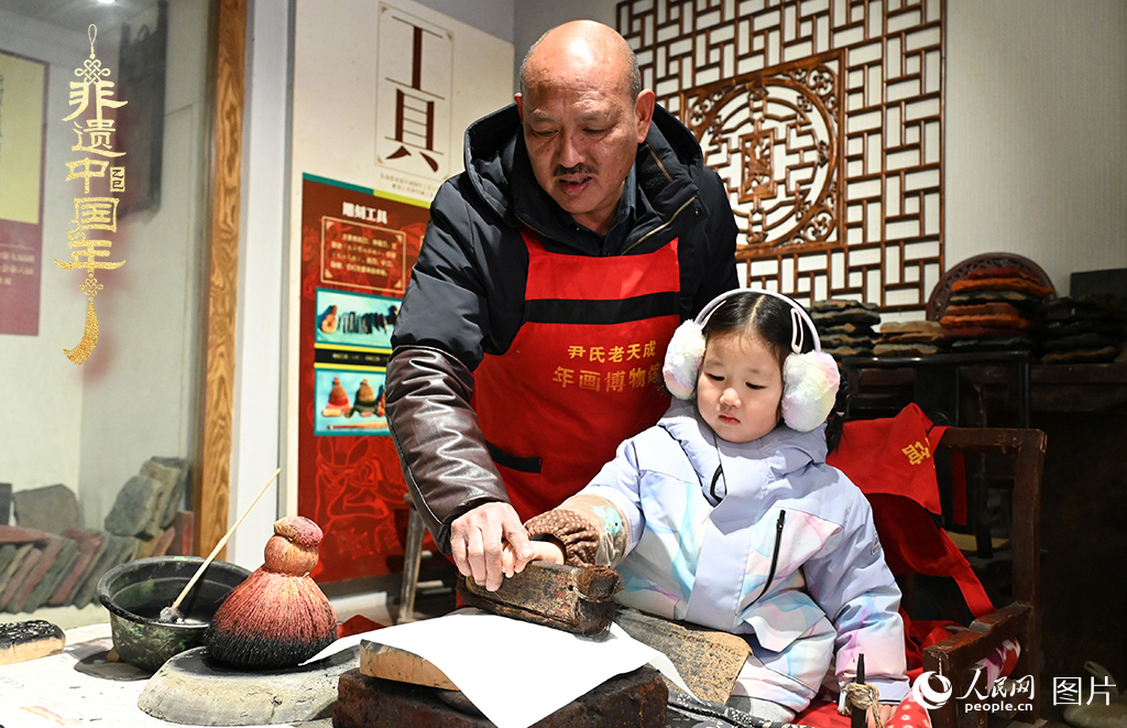 2025年1月27日，河南開封朱仙鎮(zhèn)木版年畫藝人尹國法指導(dǎo)小朋友研習(xí)年畫印制技藝。朱仙鎮(zhèn)木版年畫源自漢唐壁畫藝術(shù)，是中國木版年畫的鼻祖。2006年5月20日，朱仙鎮(zhèn)木版年畫經(jīng)國務(wù)院批準(zhǔn)列入第一批國家級非物質(zhì)文化遺產(chǎn)名錄。人民網(wǎng)記者 王玉興攝