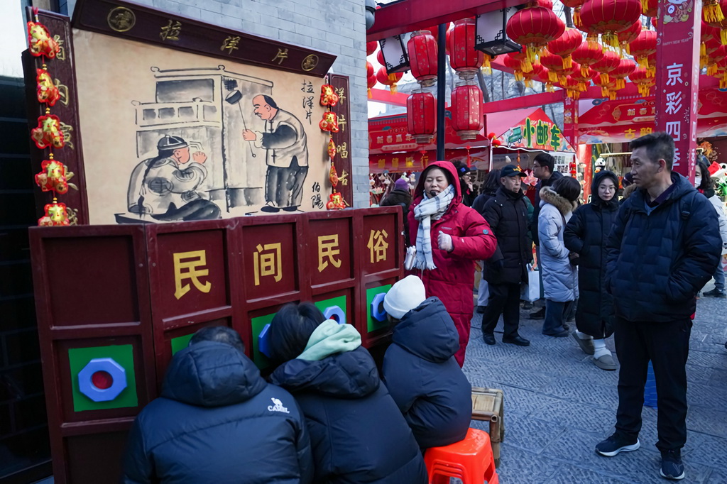 1月29日，游客在位于北京中軸線上的前門大街步行街區(qū)域觀看拉洋片。新華社記者 鞠煥宗 攝