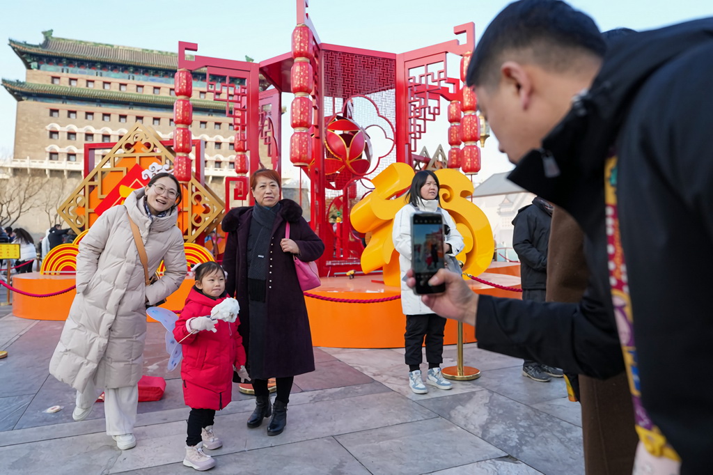 1月29日，在位于北京中軸線上的前門(mén)大街，幾位游客與新春景觀裝置合影留念。新華社記者 鞠煥宗 攝