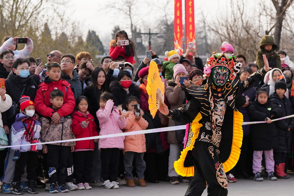 1月31日，游客在景山公園的萬(wàn)春嘉年華上觀看川劇變臉表演。新華社記者 鞠煥宗 攝